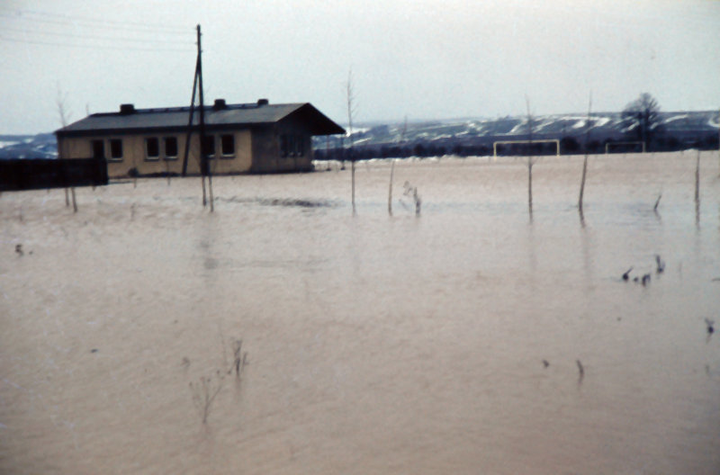 Sportplatz mit Sportlerheim bei Hochwasser. 